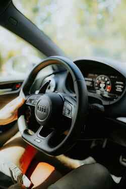Seitliche Nahaufnahme des Lenkrades in einem Audi, das eine Person hält.