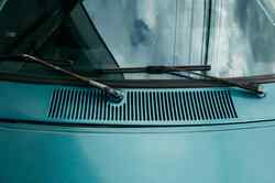 Rostige Scheibenwischer eines blauen Autos.