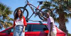 Eine Frau und ein Mann stehen neben einem roten seat ibiza, auf welchem Fahrräder montiert sind.