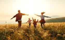 Eine Mann, eine Frau und zwei Kinder toben auf einem Feld im Sonnenuntergang herum