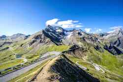 Es ist ein grün bewachsenes Gebirge zu sehen durch welches eine Straße in Serpentinen verläuft.