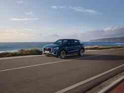 Ein dunkelblauer Audi Q2 fährt eine Küstenstraße entlang