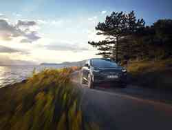 Dynamische Frontansicht eines Audi Q4 e-tron, der durch eine Naturkulisse fährt