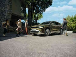 Eine Familie geht auf einen grünen Škoda Enyaq zu