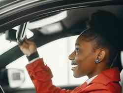 Eine Frau blickt in den Spiegel eines Autos.