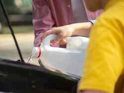 Jemand füllt Scheibenwasser in einem Auto nach.