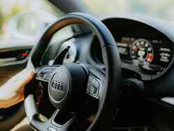 Seitliche Nahaufnahme des Lenkrades in einem Audi, das eine Person hält.
