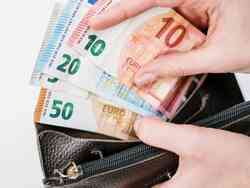 Jemand hält Euro-Scheine und eine Geldtasche in den Händen.