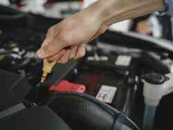 Jemand zieht am Ölmessstab eines Auto.