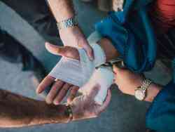 Jemand bandagiert die Hand einer Person