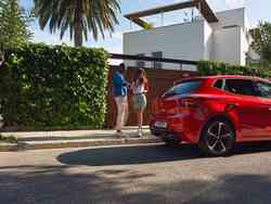 Eine Frau und ein Mann schauen sich einen roten Seat Ibiza an.