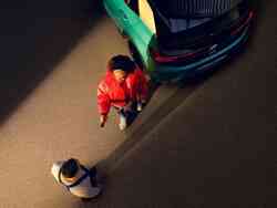 eine Frau und ein Mechaniker unterhalten sich vor einem blauen VW iD.3