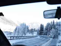 Eine verschneite Autobahn aus der Windschutzscheibe eines fahrenden Autos fotografiert.