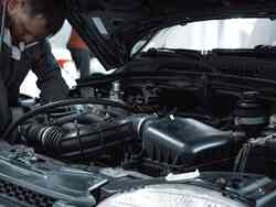 Die Motorhaube eines Fahrzeuges ist geöffnet. Ein Mechaniker hat beide seine Hände in der Motorhaube und repariert etwas. Die Motorhaube eines Fahrzeuges ist geöffnet. Ein Mechaniker hat beide seine Hände in der Motorhaube und repariert etwas.