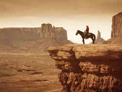 Ein Cowboy sitzt auf einem Pferd, das an einer Klippe steht.