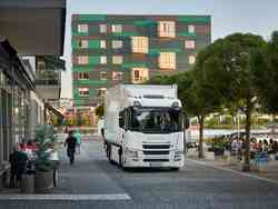 Ein weißer Scania LKW fährt durch eine belebte Straße.