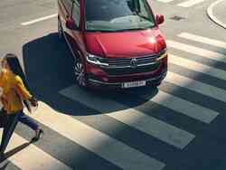 Eine Frau geht über die Straße und ein VW Multivan biegt gerade nach ihr ab.