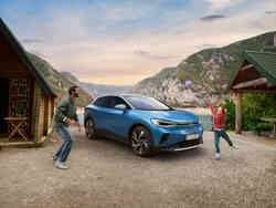 Eine Frau geht zu einem roter SUV, der gerade aufgeladen wird