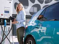 Frau steht an der Ladesäule neben einem Elektroauto