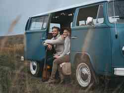 Frau und Mann sitzen in einem blauen VW Bus.