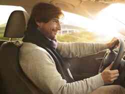 Mann sitzt glücklich am Steuer eines Fahrzeugs