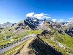 Es ist ein grün bewachsenes Gebirge zu sehen durch welches eine Straße in Serpentinen verläuft.