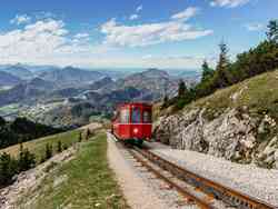 Die Schafbergbahn: eine Zahnradbahn fährt auf den Gipfel des Schafbergs auf 1.732 Meter Höhe. Im Hintergrund ist das Tal zu sehen.