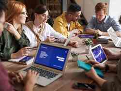 Mehrere Menschen sitzen am Tisch mit ihren Laptops.