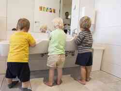 Drei Kinder waschen sich die Hände.
