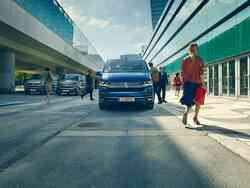 Blauer VW Caravelle auf einer Straße mit Autos und Menschen