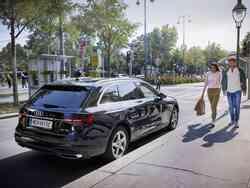 Ein Mann und eine Frau spazieren an einem schwarzen Audi vorbei.