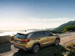 Seitliche Heckansicht des Škoda Kodiaq vor einer See- und Bergkulisse