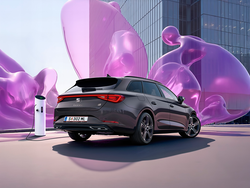 Seitliche Heckansicht des SEAT Leon Kombi, der neben eine Ladesäule steht. Im Hintergrund sind violette Blasen
